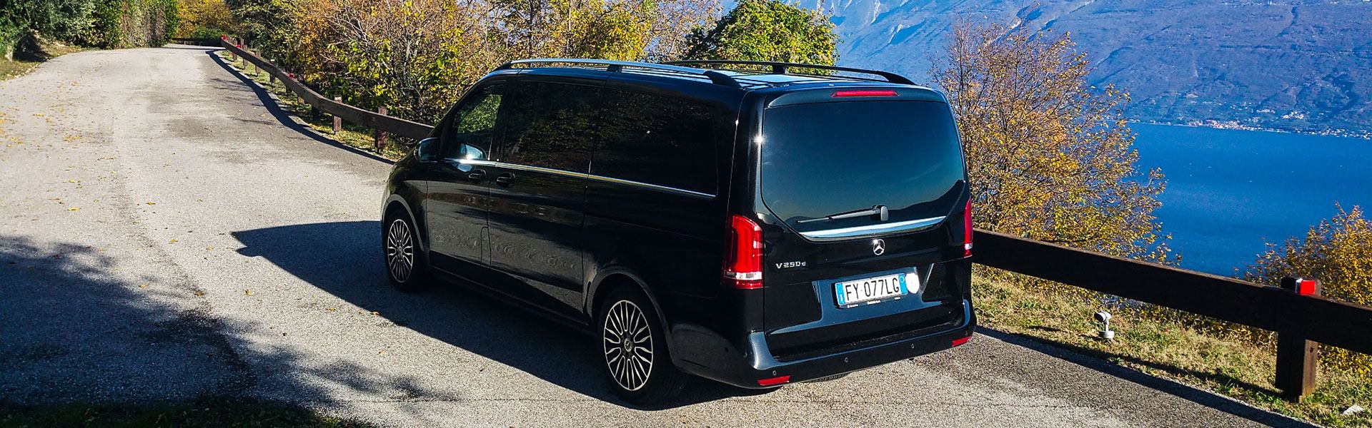 Minivan nero su una strada panoramica sopra un lago